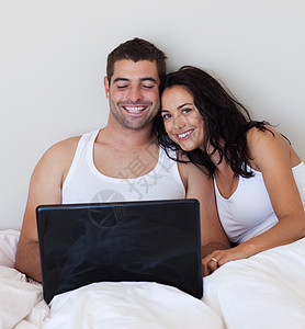 在床上使用笔记本电脑的一对有吸引力的夫妇图片