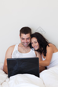 夫妇在卧室用笔记本电脑微笑图片