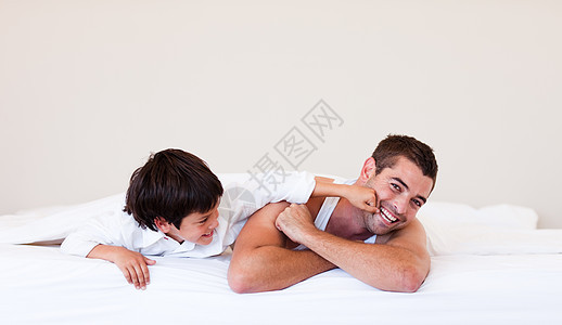 父子在床上玩得开心快乐女儿儿子妈妈父亲乐趣拥抱孩子生活后代图片