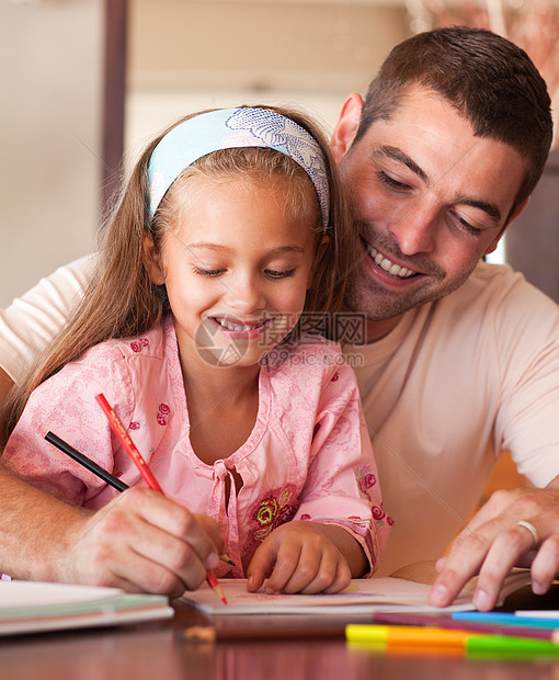 快乐的父亲帮助她的女儿做家庭功课图片