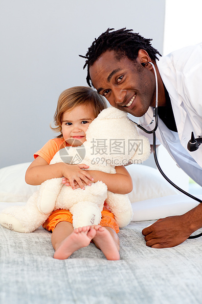 在医院检查一个小女孩时微笑的医生;图片