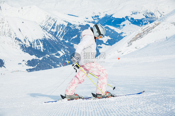 快乐的小女孩在下坡滑雪衣服季节蓝色天空风镜青年配备头盔滑雪者女孩图片