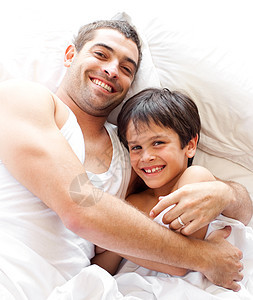 父亲和儿子在看床上的照相机时 自证其罪图片