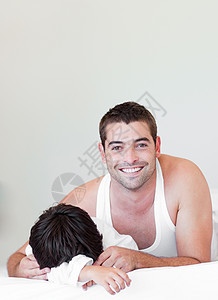 吸引人的父亲和儿子看着床上的照相机 看图片