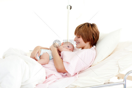 与床上新生婴儿一起微笑的病人图片