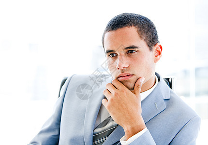 坐在办公桌前的一位沉浸在思想中的青年商务人士的肖像图片