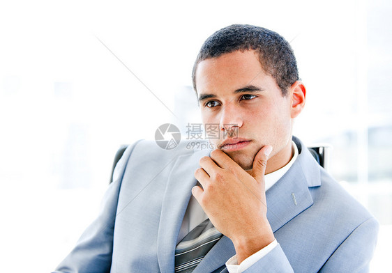 坐在办公桌前的一位沉浸在思想中的青年商务人士的肖像图片
