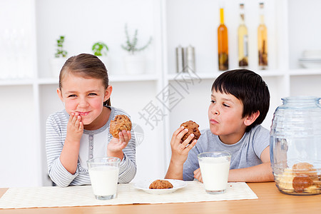 快乐的兄弟姐妹吃饼干和喝牛奶图片