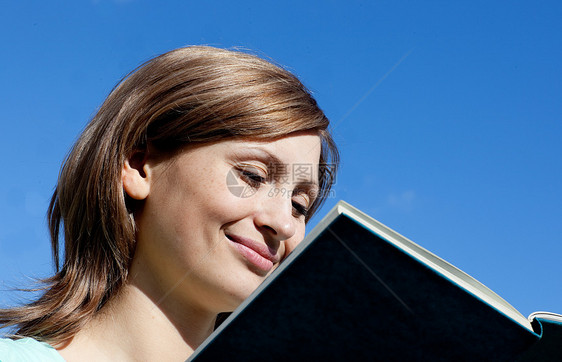 可爱的女士正在户外阅读一本书图片
