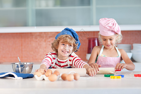 快乐的兄弟姐妹们做饼干乐趣孩子们女孩孩子烹饪童年食物厨房闲暇微笑图片