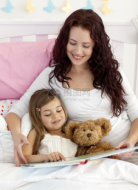 快乐的母亲和女儿在床上读书图片