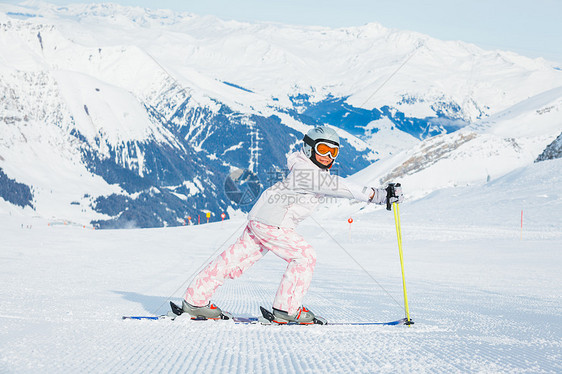 快乐的小女孩在下坡滑雪女性配备娱乐青年季节蓝色风镜活动靴子运动图片