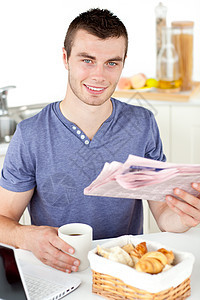 持着杯子和报纸笑着微笑着的青年男子商业文章男性食物领带男人饮料厨房笔记本网络图片