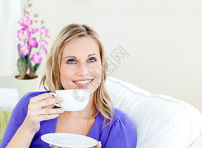 光亮的女士享受着她的咖啡 坐在生活沙发上图片
