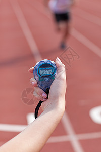 一名持有计时表以衡量业绩的妇女的近身检查运动员男人紧迫感女士体育场间隔跑步时间短跑小时图片