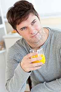 迷人的年轻男人 在厨房里喝橙子汁橙子房间玻璃魅力微笑果汁桌子男性幸福图片