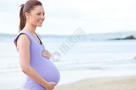 可爱的孕妇站在沙滩上图片