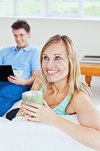 年轻夫妇 男人用笔记本电脑时女人喝茶图片