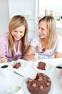 在厨房里吃巧克力蛋糕的快乐女性朋友图片