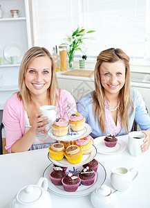 两名女性朋友吃糕点和喝果汁的肖像图片