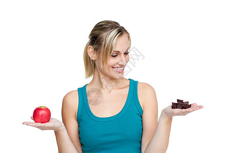 年青女人比较苹果和巧克力图片