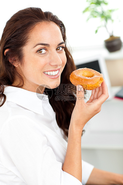拿着甜甜圈微笑他的西班牙女商务人士图片