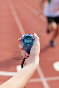 一名持有计时表以衡量业绩的妇女的近身检查短跑运动跑步间隔紧迫感测量手表男人记录女士图片