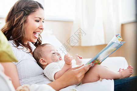 迷人的妈妈在一本书里给可爱的小儿子看图片