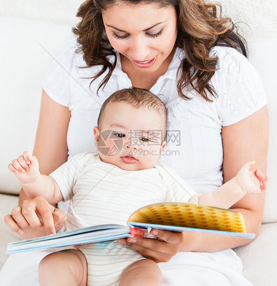 明亮的母亲在一本书中给可爱的小儿子展示图像青年压痛孩子后代沙发妈妈女士投标拥抱家庭图片