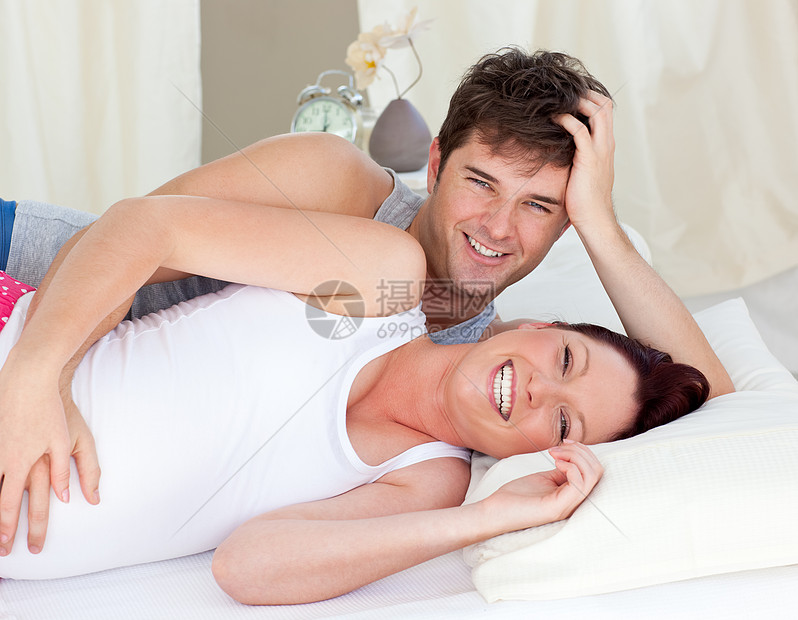 与丈夫躺在床上的有笑笑的caucasian孕妇图片