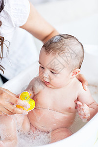 在洗澡时把一个婴儿关上 和一只塑料鸭玩耍图片