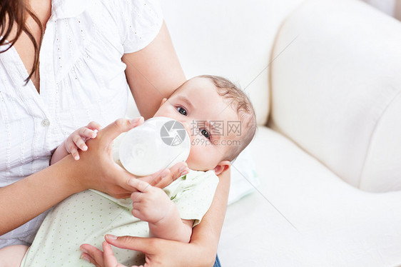 在他母亲的手臂上 紧贴一个婴儿 喝牛奶当午餐图片