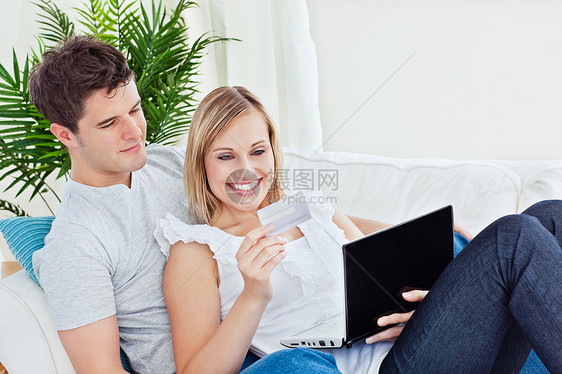 幸福的情侣用信用卡和笔记本电脑 在沙发上休息图片