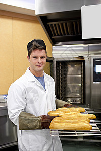 快乐的面包师展示他的面包包 在摄像机上 站在他身旁图片