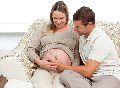 可爱男人感觉自己的宝宝 手放在妻子的肚子上图片