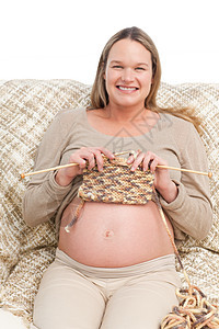 坐在沙发上的快乐的孕妇编织图片