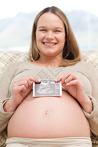 坐在沙发上 怀着回声法的幸福孕妇图片