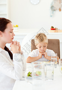 集中精神的小男孩 在吃东西前和妈妈一起祈祷图片
