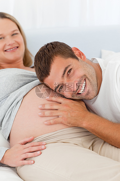 欣喜的男人倾听其怀孕妻子的肚子图片