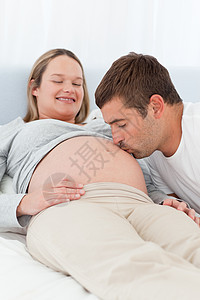 骄傲的未来父亲亲吻妻子的肚子图片