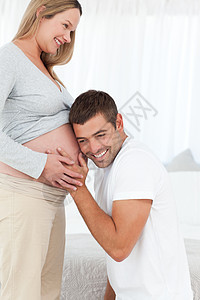 快乐的膝盖男人听着他怀孕妻子的肚子图片