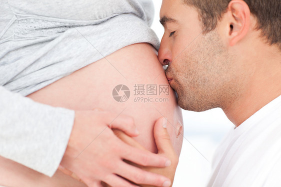 近距离亲吻他可爱的怀孕妻子肚腹的男人膝盖情感微笑女士母亲父母女性享受喜悦爸爸图片
