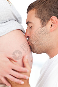 亲吻宝宝未来的父亲亲吻他怀孕妻子的肚腹背景