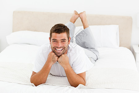 英俊的男人笑着躺在床上图片