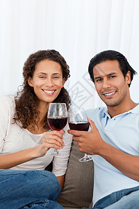 快乐的一对夫妇在沙发上杯红酒图片