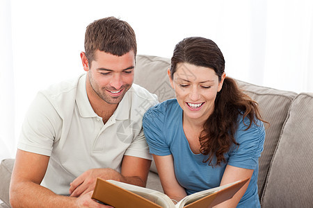 可爱的情侣在沙发上一起看书图片