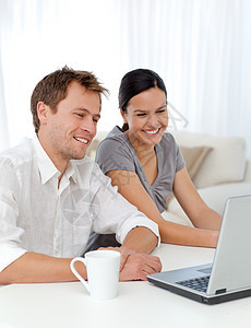 可爱的情侣在看笔记本电脑录像时笑着笑图片