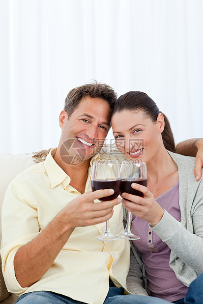 可爱的情侣在沙发上喝红酒图片