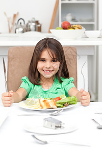 抱着叉子吃意大利面和沙拉的可爱小女孩图片