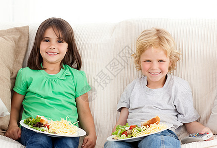 快乐的兄弟姐妹一起吃电视晚饭图片